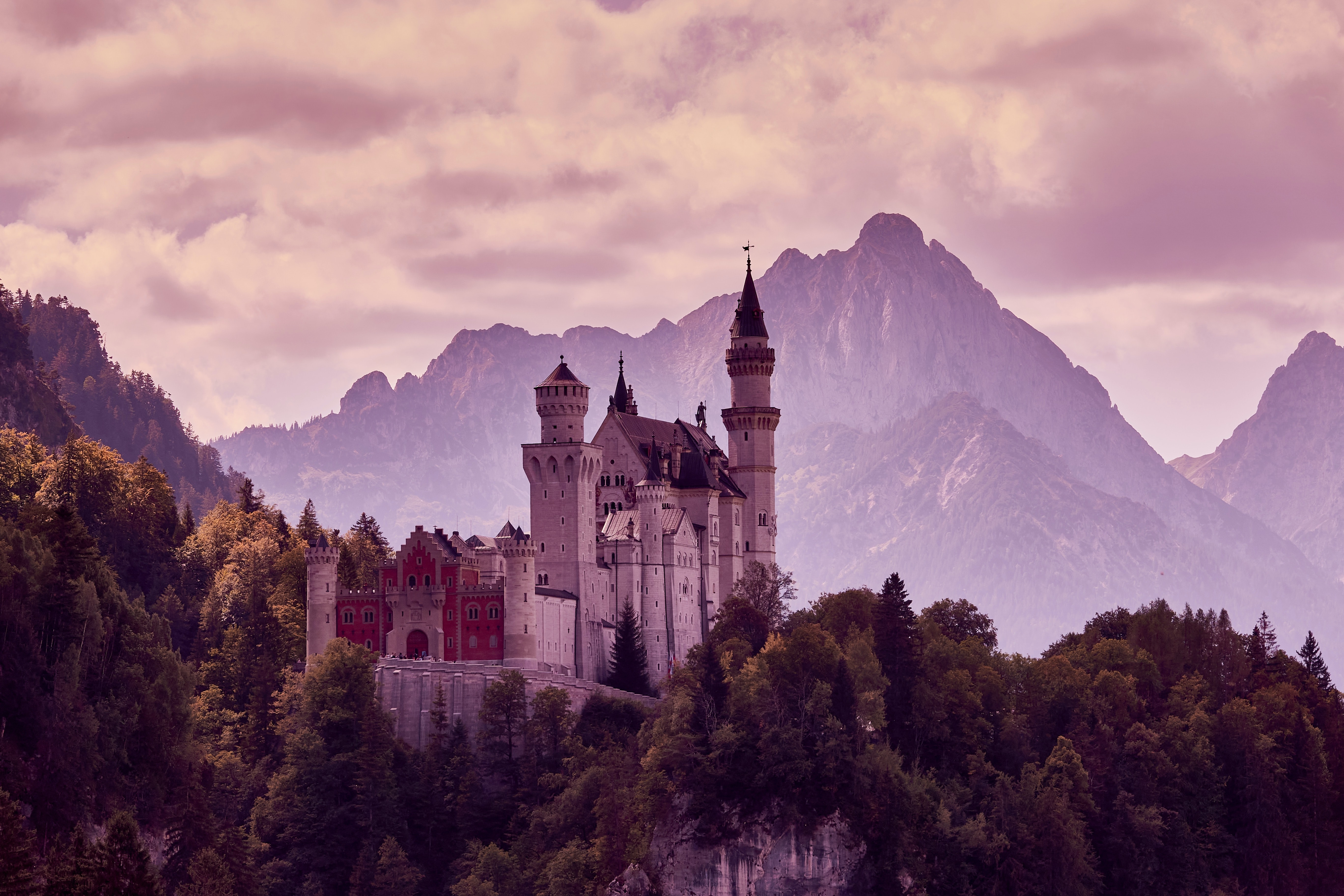 Un castillo entre montañas y bosques al atardecer